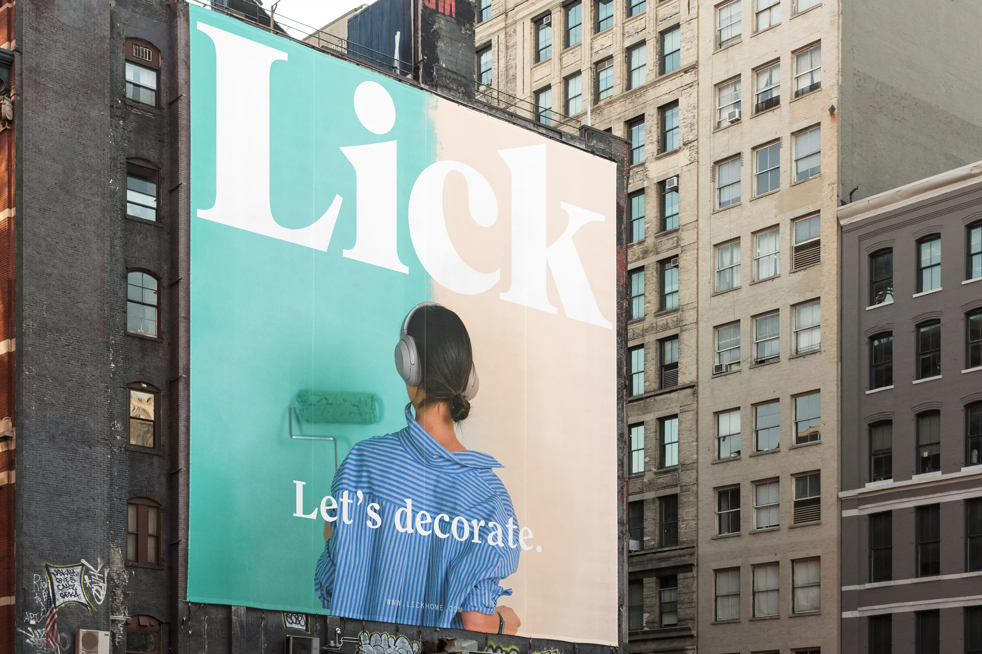 Outdoor advertisement featuring a woman with headphones, holding a paint roller, promoting the Lick brand with the slogan 'Let's decorate.'