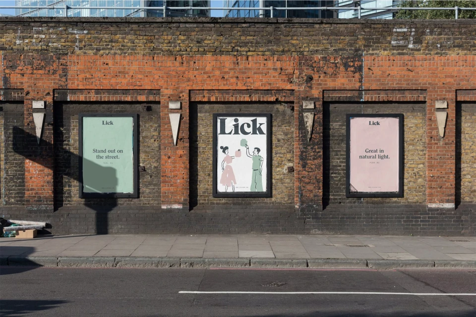 Outdoor advertising billboards on brick wall feature illustrations of people and product branding for Lick paint and home decor.
