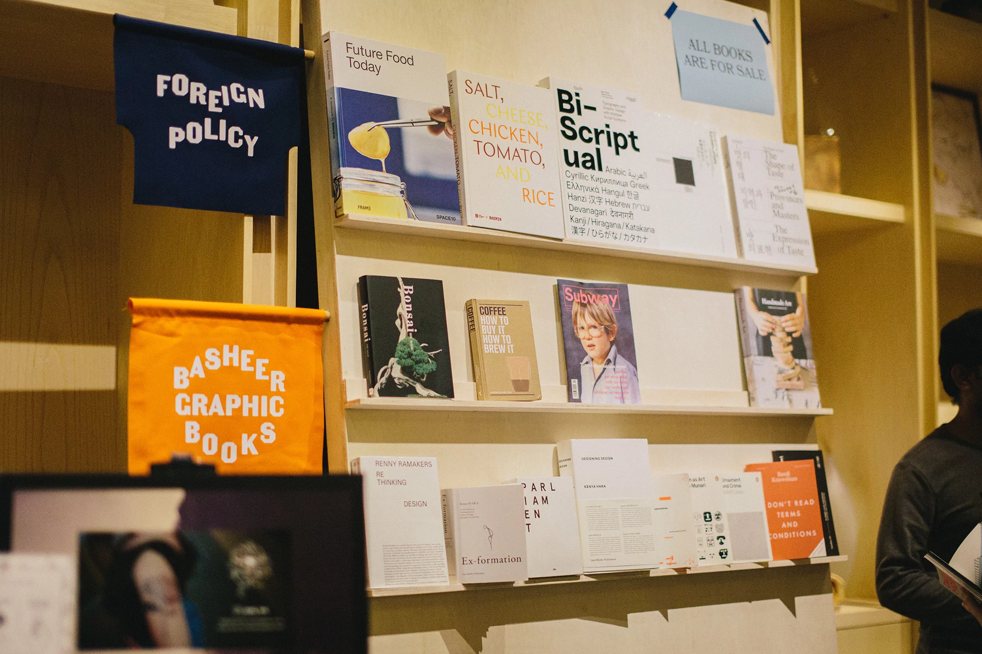 Books displayed on a shelf, including titles like 'Future Food Today,' 'Salt, Cheese, Chicken, Tomato, Rice,' and 'Bi-Scriptual.'