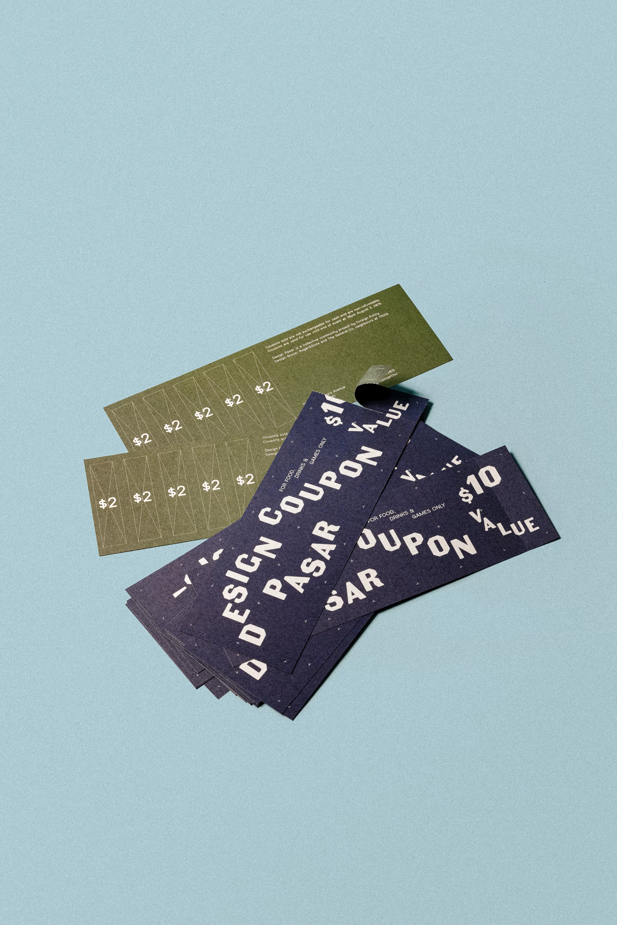 Graphic design coupons in shades of olive green and navy blue scattered on a powder-blue surface, showcasing promotional offers.