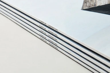 Close-up of a stacked stack of printed brochures with visible typography reading FLOORPLAN - SUPERNATURAL along the spine against a neutral background