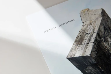 Text reading Floorplan Supernatural on white paper next to a textured concrete block