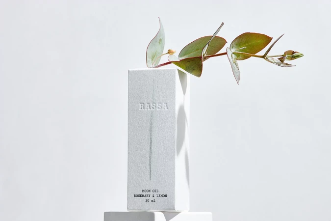 Rassa moon oil, rosemary and lemon product shot. Box and eucalyptus on white backdrop for beauty and wellness industry product marketing.