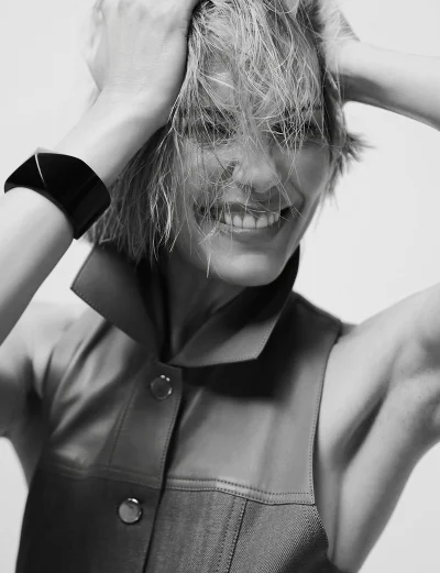 Leslie Bibb smiling with wet hair in a sleeveless top and black cuff bracelet against a plain light background
