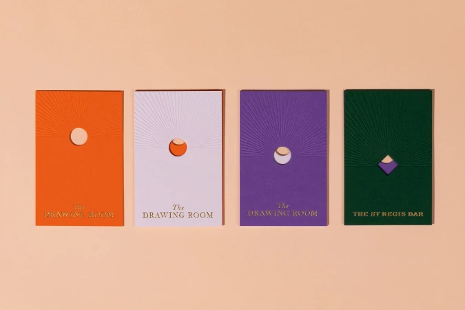 Four colorful embossed cards with minimalist design, featuring 'The Drawing Room' and 'The St Regis Bar' text against a peach background.