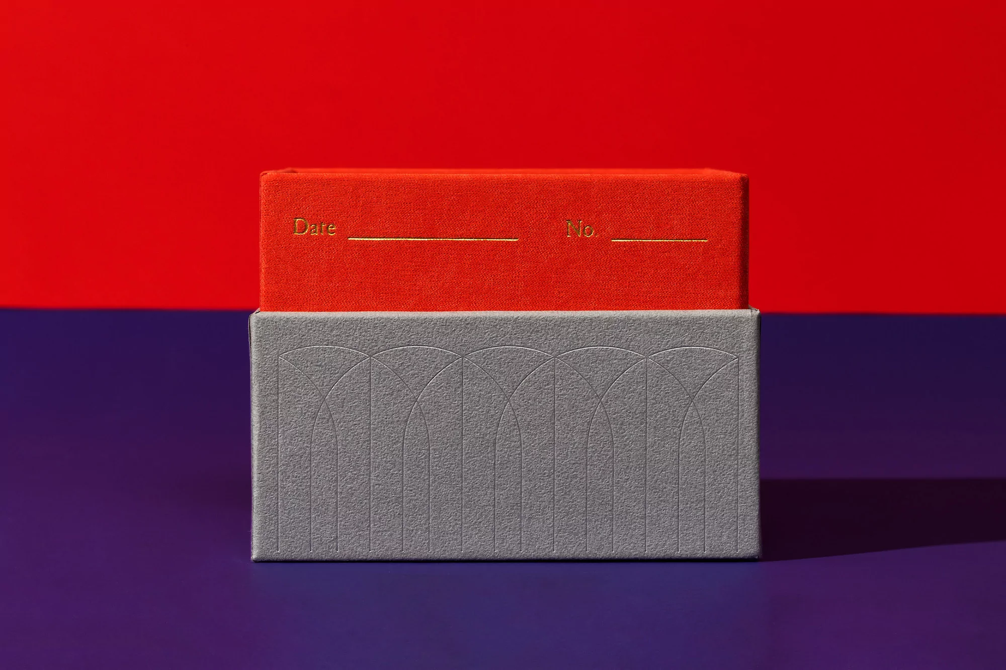Rectangular orange journal on top of gray box, against a split red and purple background.  Date and No. headings.