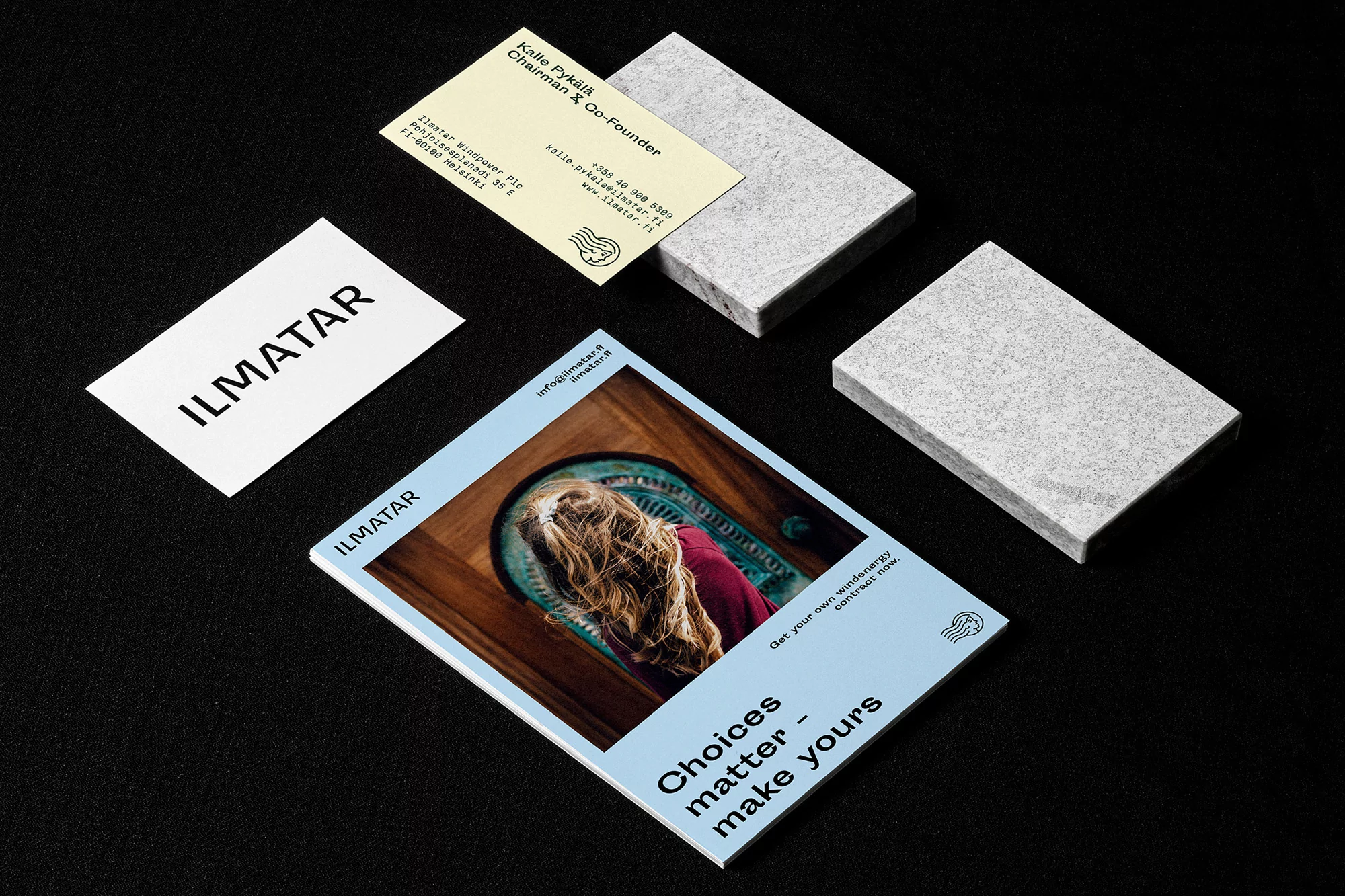 Promotional materials featuring a brochure and business cards with the company logo and contact information on a black surface.