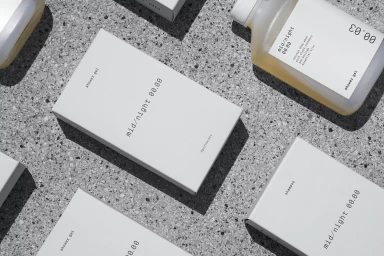 Minimalist skincare product packaging and bottles featuring clean typography on a textured grey stone surface