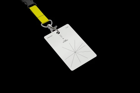 White ID badge with starburst graphic and black text attached to a yellow lanyard against a solid black background.