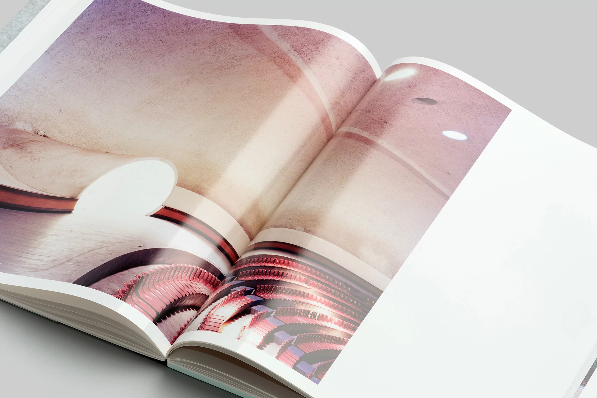Open magazine featuring an architectural interior with curved walls and diffused lighting, showcasing a visually compelling space.