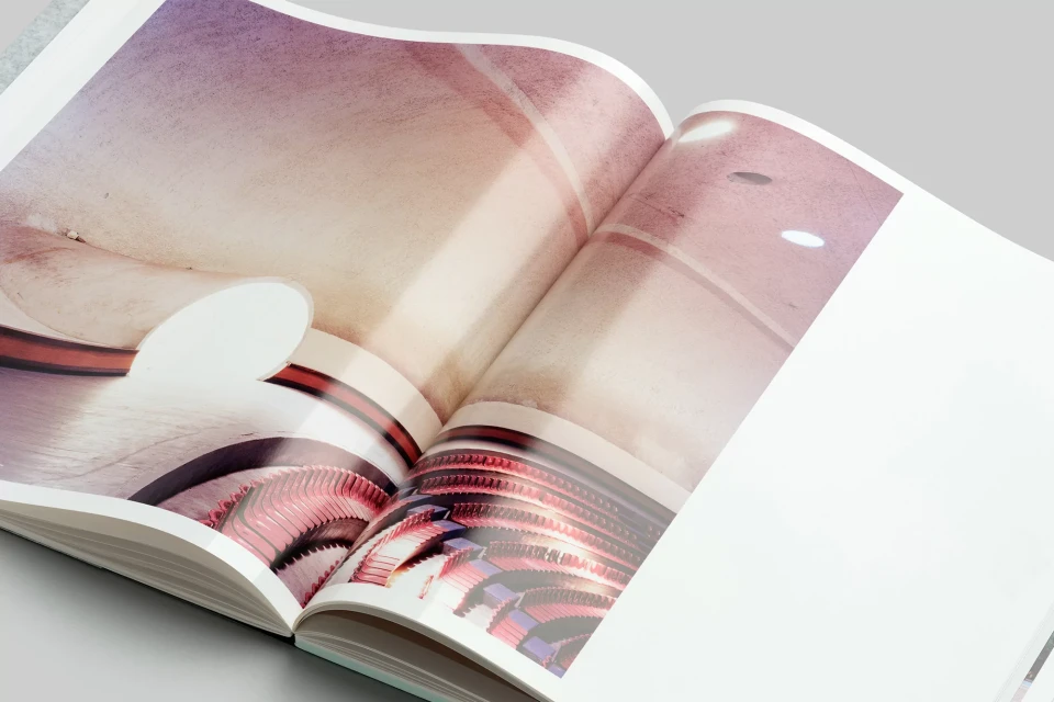 Open magazine featuring an architectural interior with curved walls and diffused lighting, showcasing a visually compelling space.