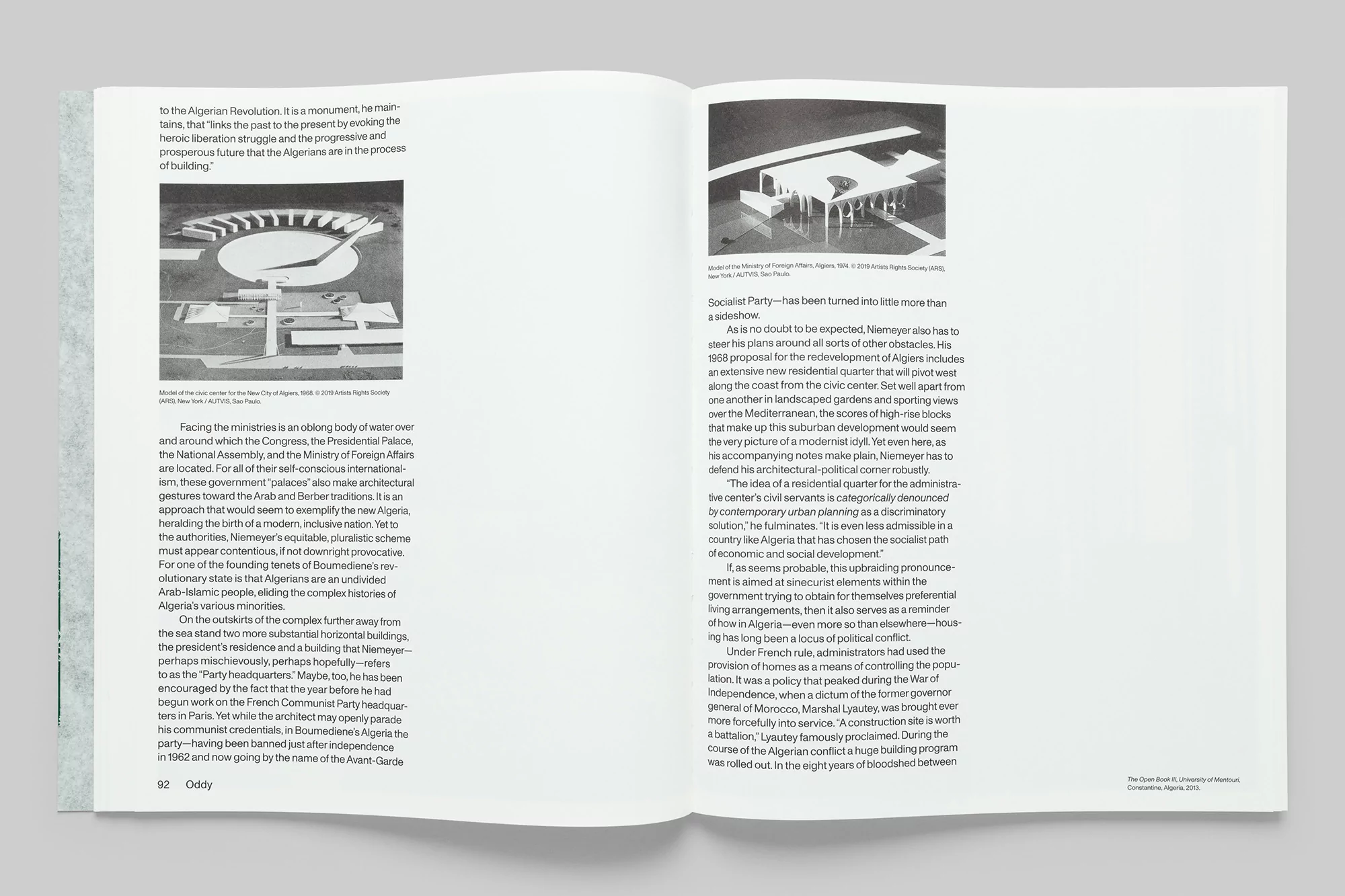 Monochrome photo of architectural models and text from open book, showcasing building designs, text descriptions, and architectural layout.