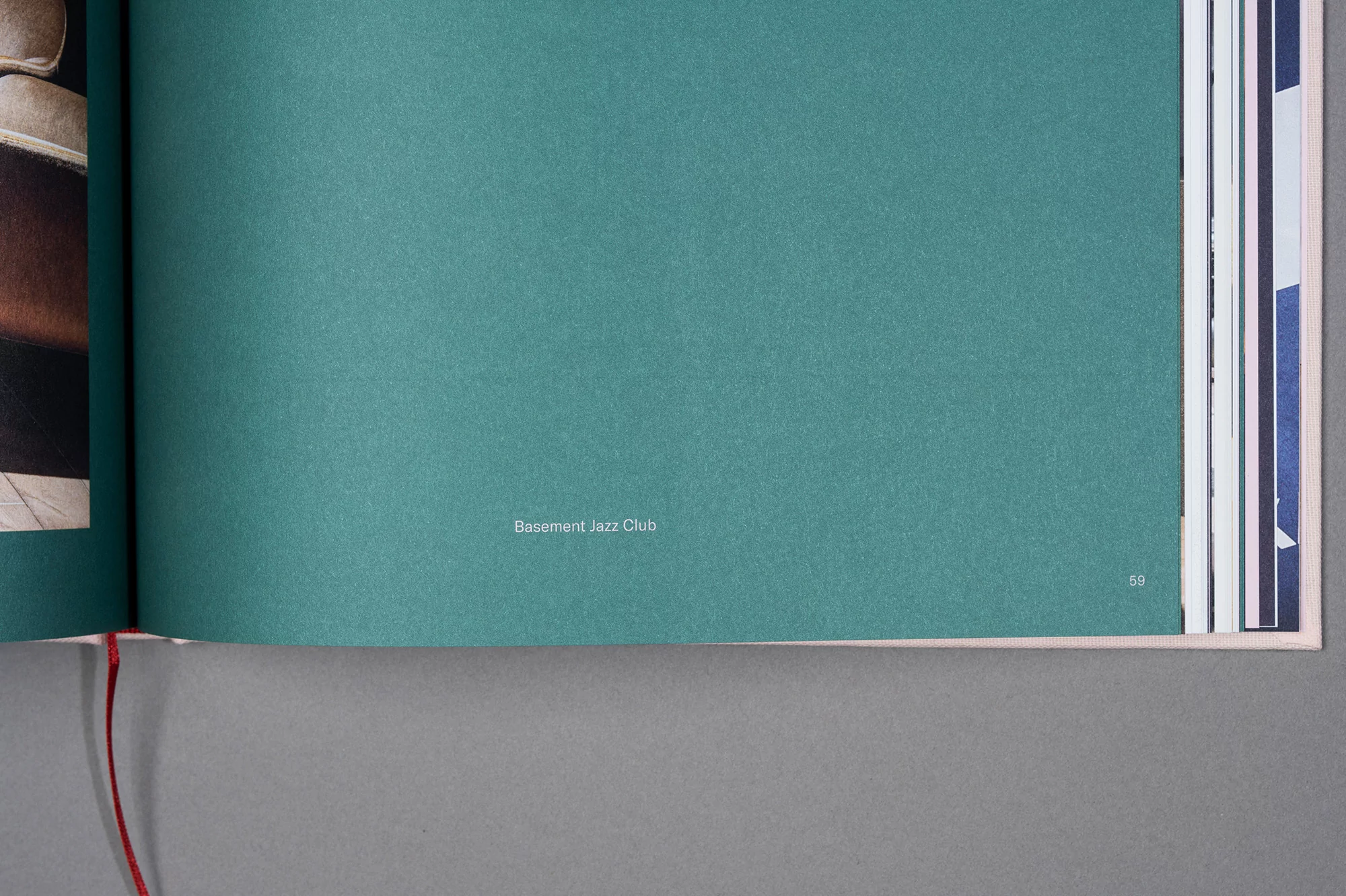 Open book with textured teal page featuring the text 'Basement Jazz Club', surrounded by other pages with hints of imagery.