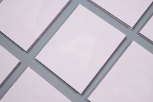 Multiple pale pink books featuring a debossed letter A on the cover arranged in a neat grid on a grey surface.