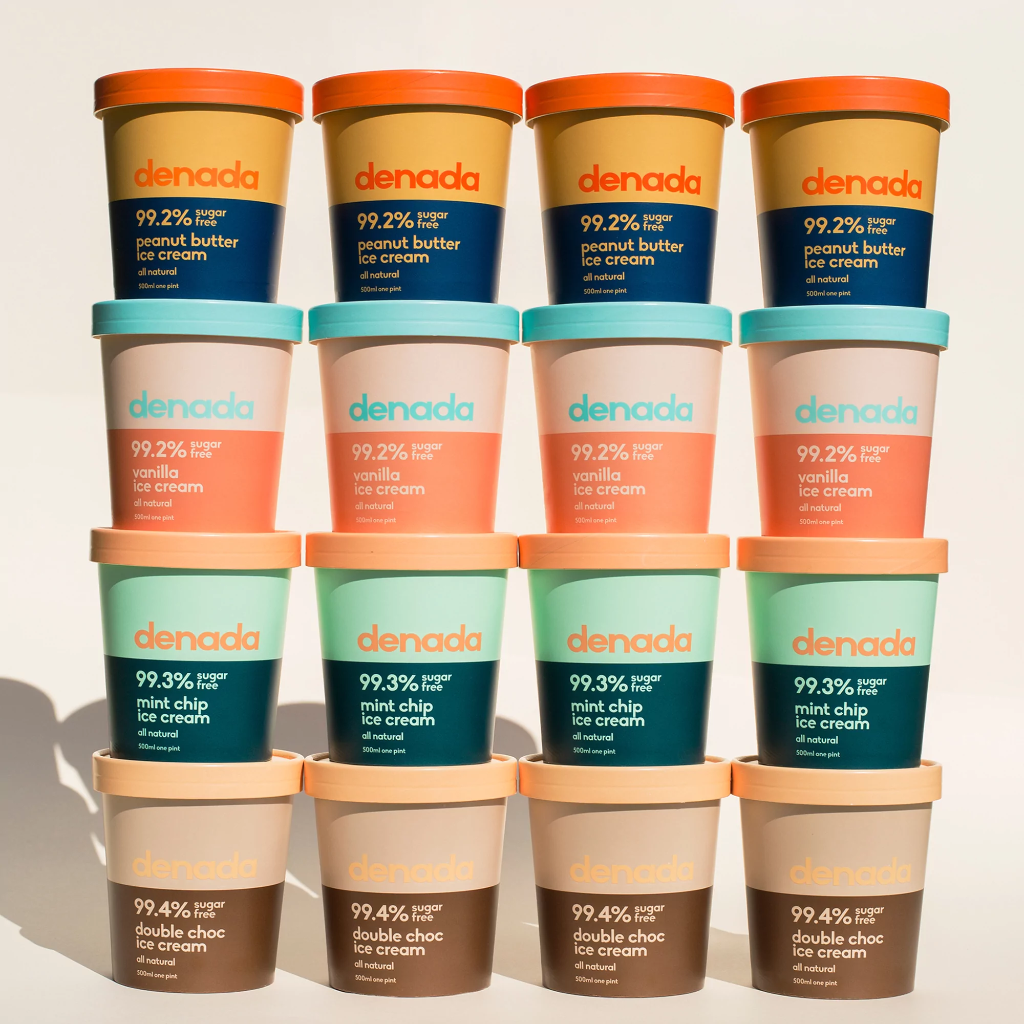 Stacked tubs of Denada ice cream in assorted flavors: peanut butter, vanilla, mint chip, and double chocolate, creating a vibrant dessert display.