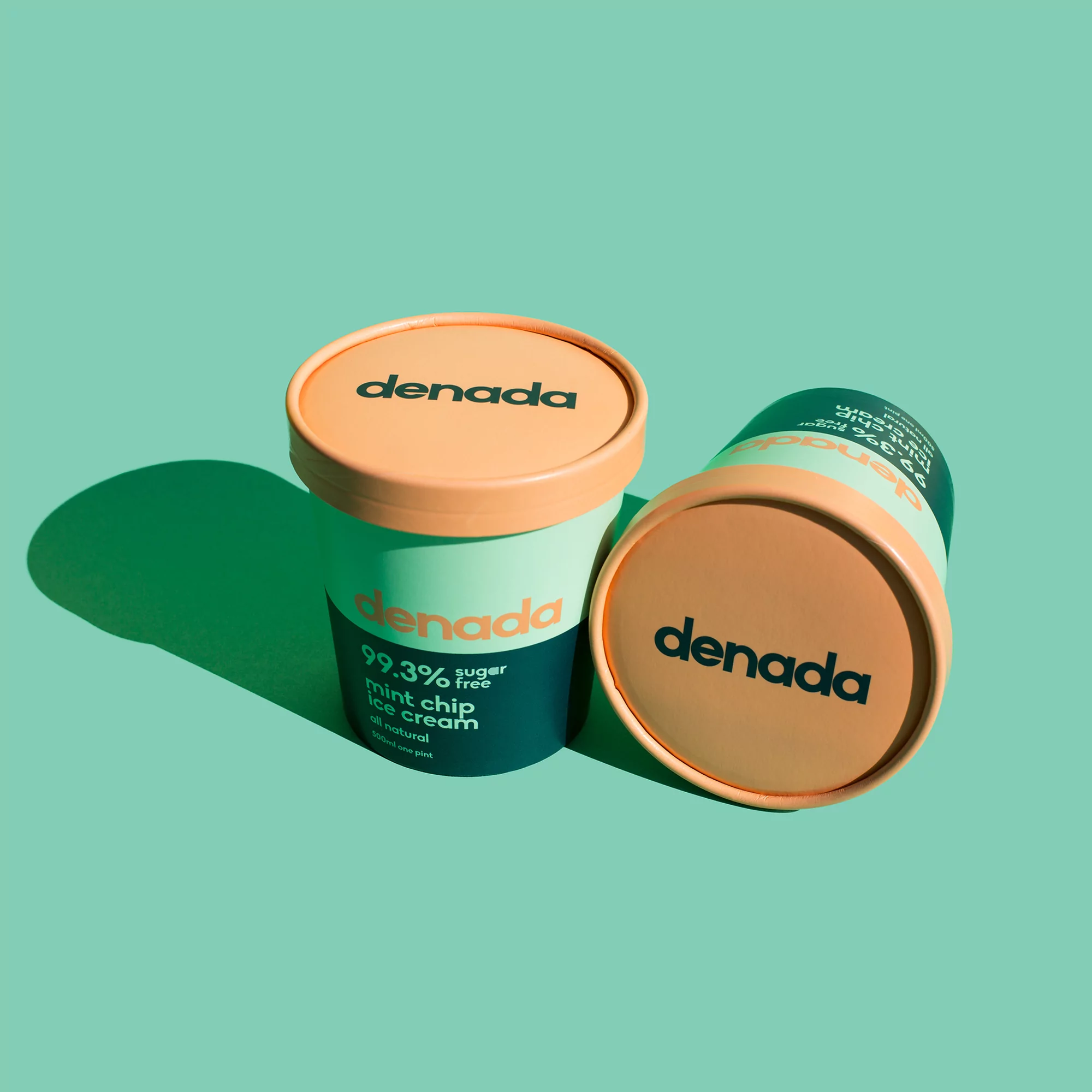 Two containers of Denada mint chip ice cream are displayed against a mint green background, one upright and one lying on its side.