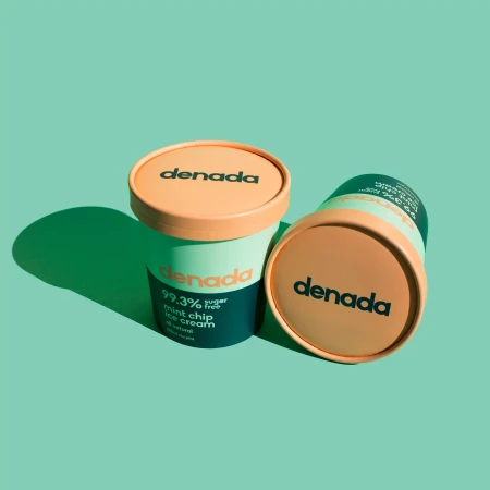 Two containers of Denada mint chip ice cream are displayed against a mint green background, one upright and one lying on its side.
