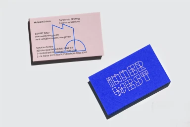 Two business cards with typography and line illustrations on pink and blue paper set against a white surface