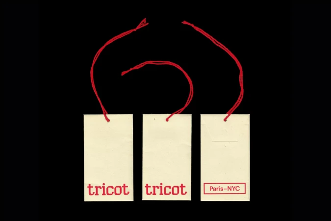 Three off-white paper tags with red string ties against a solid black background, featuring Tricot brand typography.