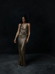 Woman wearing a textured metallic gown standing against a dark, moody background for Schön Magazine shot by Chris Noltekuhlmann.