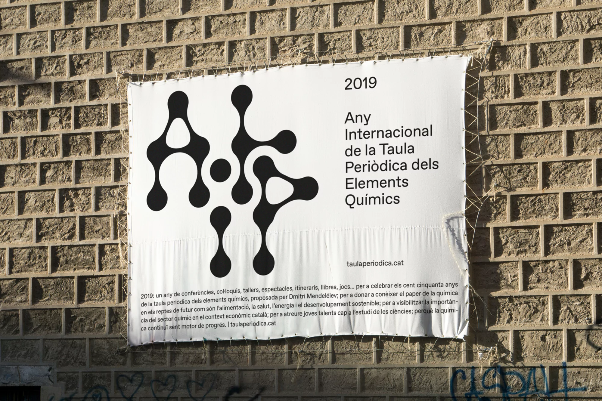 Promotional banner on a brick wall with a black graphic and text for the 'International Year of the Periodic Table of Chemical Elements'.