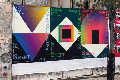 Colorful geometric graphic posters pasted on an outdoor urban wall featuring MAPP MTL branding and text elements.