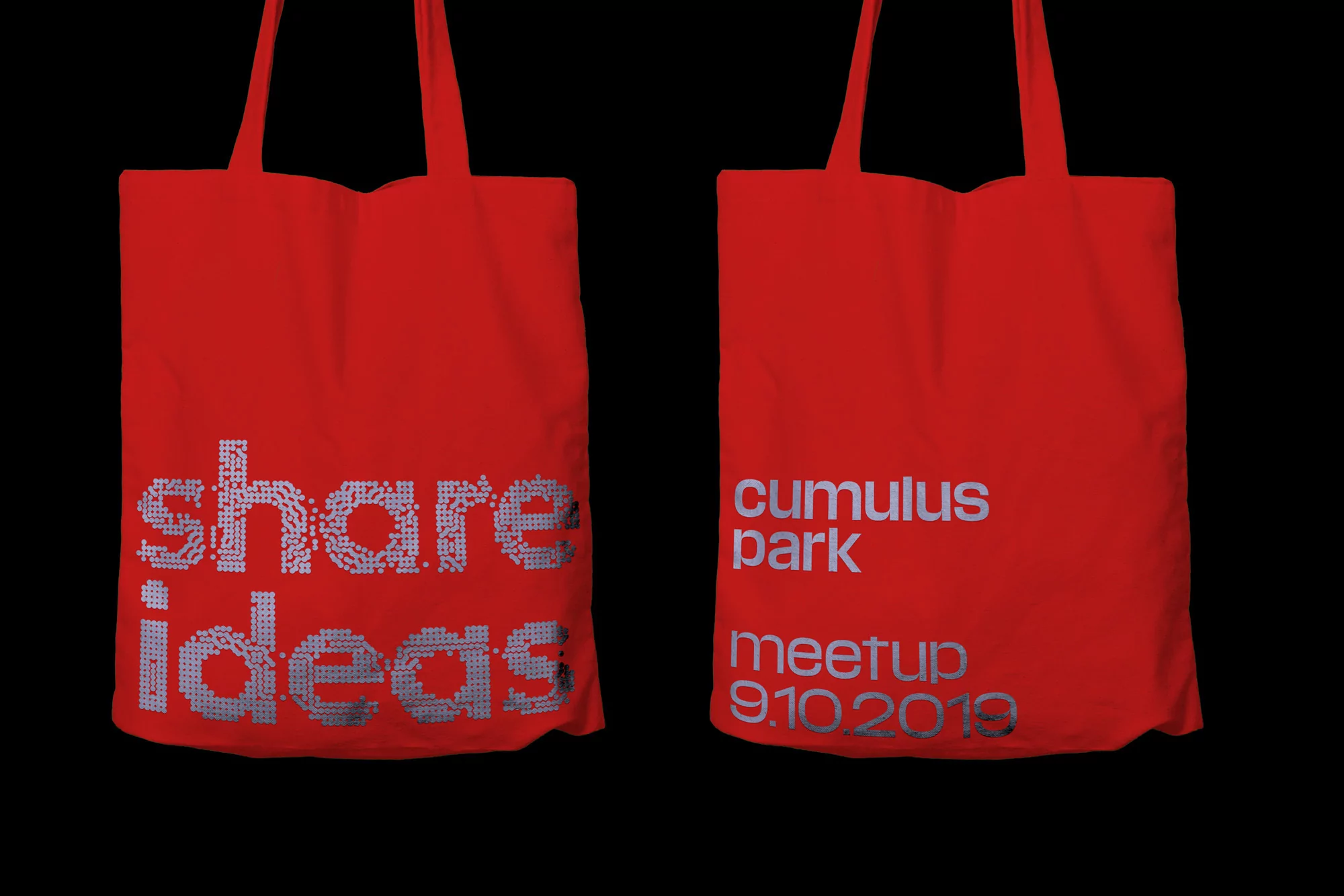 Two red tote bags featuring silver text against a black backdrop. One bag reads 'share ideas', the other 'cumulus park meetup 9.10.2019'.