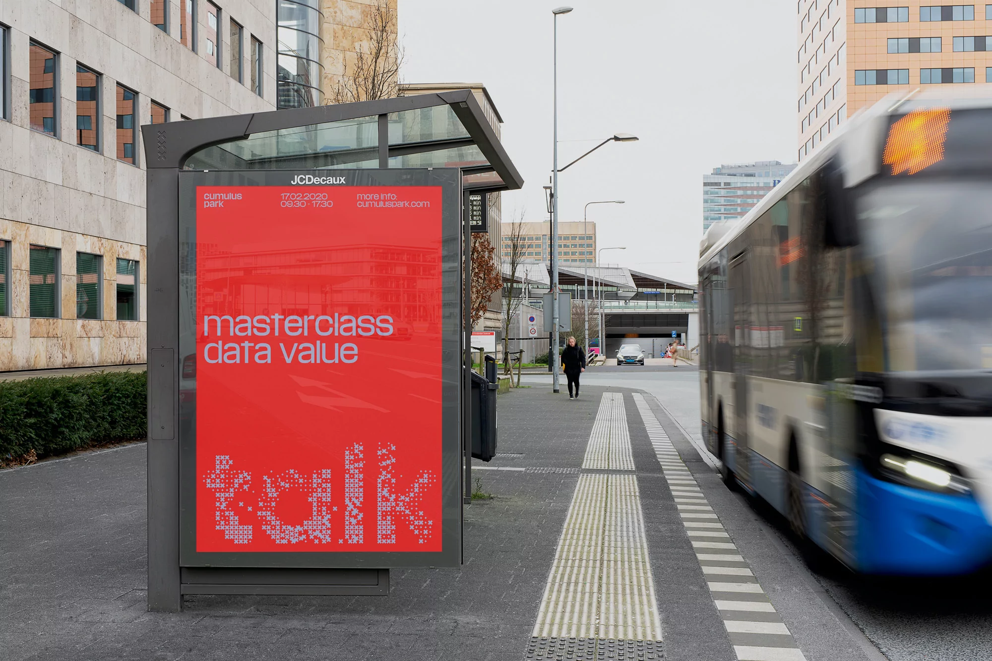Outdoor advertising for a data value masterclass, featuring a passing bus and pedestrian on a city street on an overcast day.