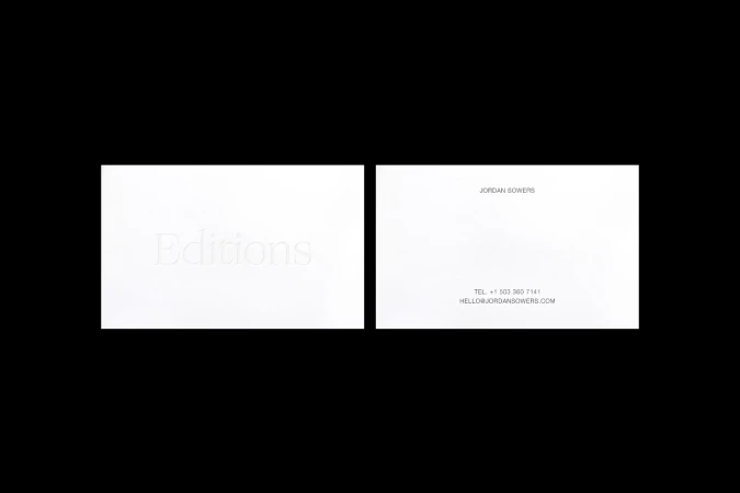 Two white business cards with subtle embossed text on a black background, featuring company name 'Editions' and contact details.