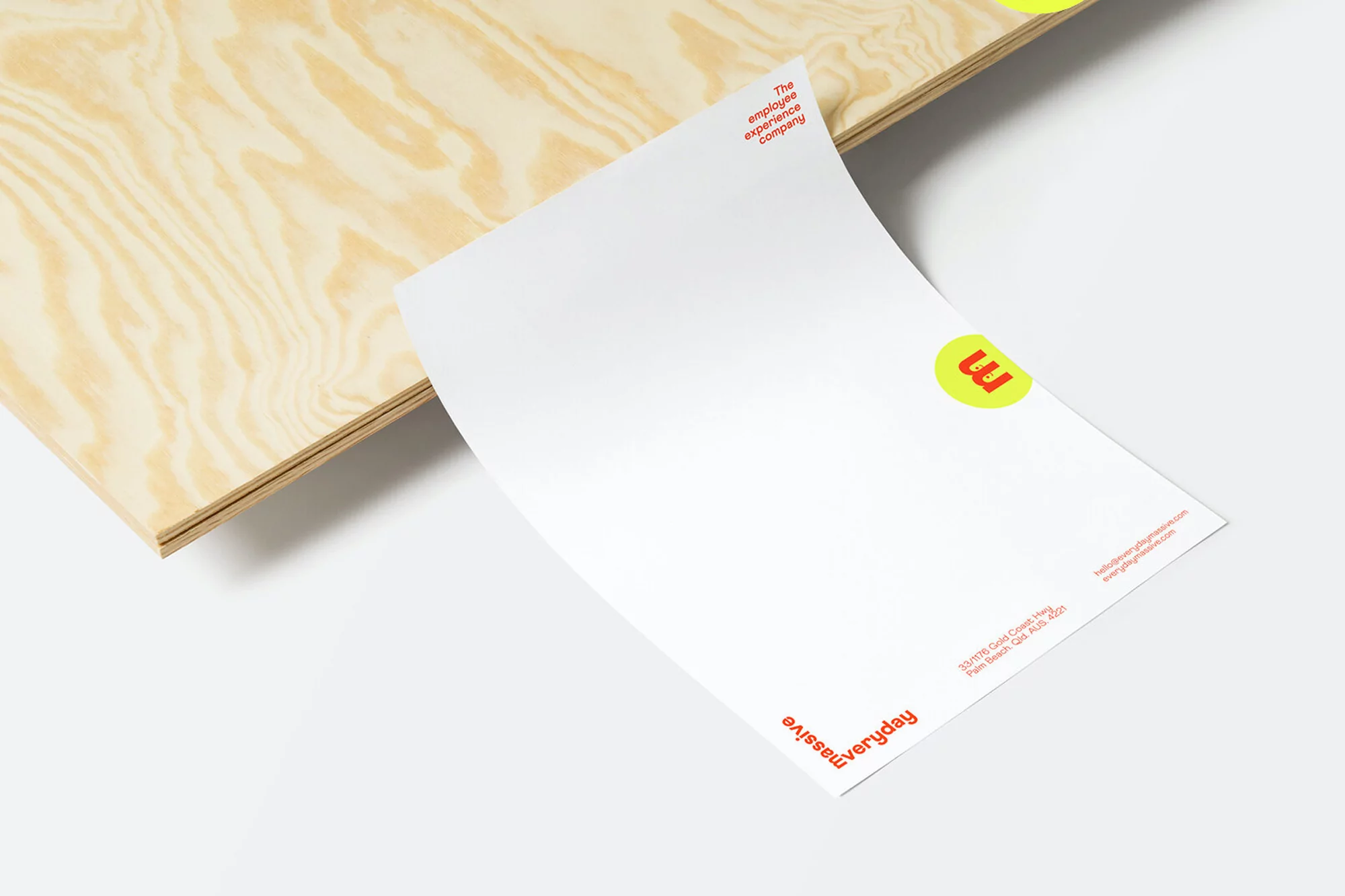 Promotional material featuring a business card with a yellow logo and printed text, displayed on a light wood board against a white background.
