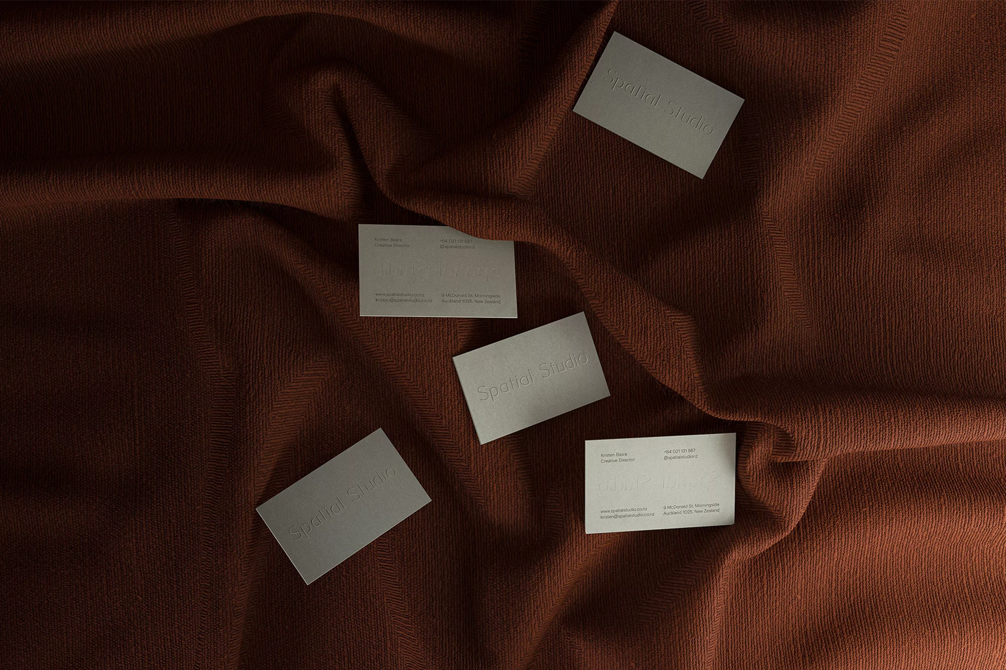Studio business cards arranged on a textured brown fabric background. Branding materials for marketing and design.