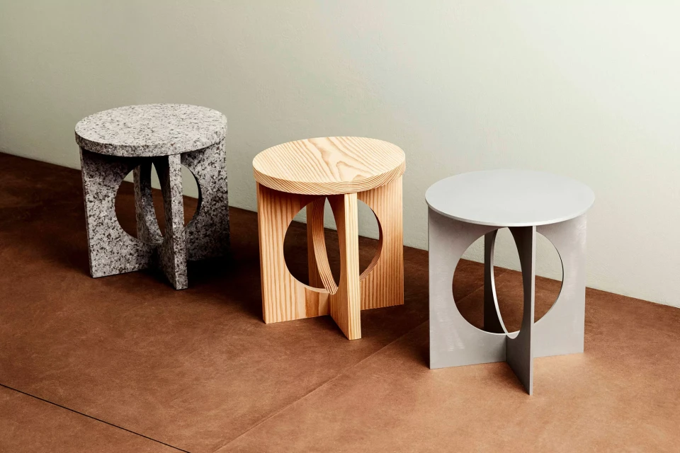 Three decorative modern accent stools with minimalist geometric design and circular cutouts displayed indoors on a tan-colored floor.