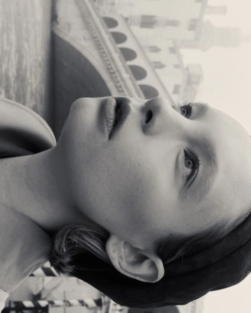 Black and white portrait of a young person looking upward with a bridge in the background, creating a serene and contemplative image.