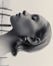 Profile portrait of a model with sleek short hair wearing a pearl earring against a light background for Numero Netherlands.