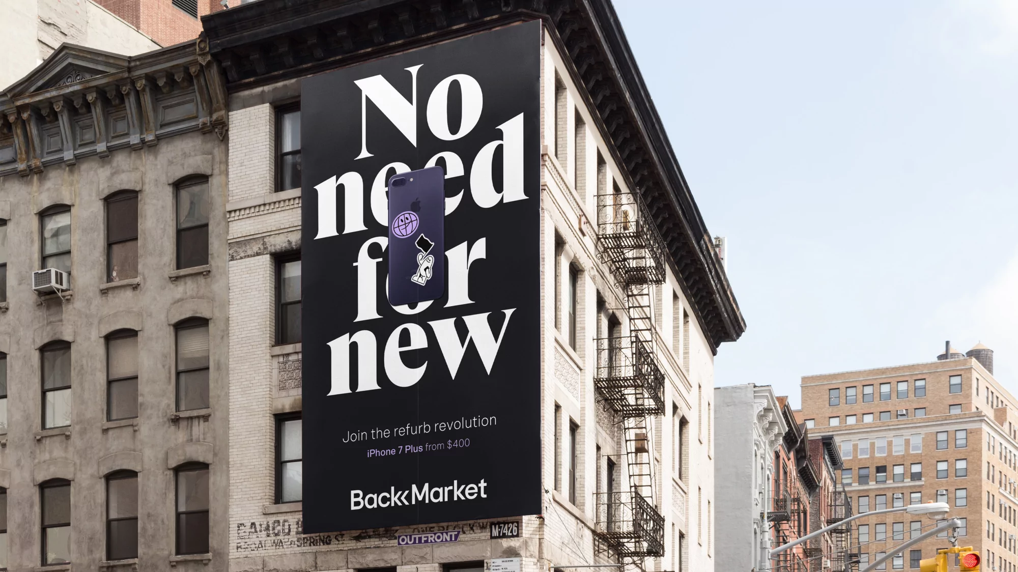 Billboard advertisement for Back Market featuring a phone with stickers, mounted on the side of a brick building in an urban setting.