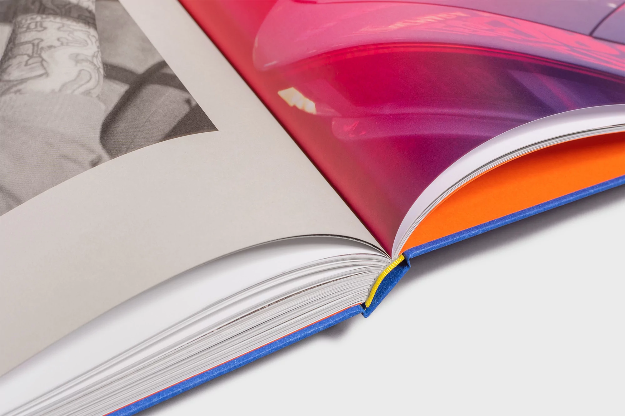 Open book with pages showcasing a black and white portrait and an abstract pink and orange image, close-up view of the binding.