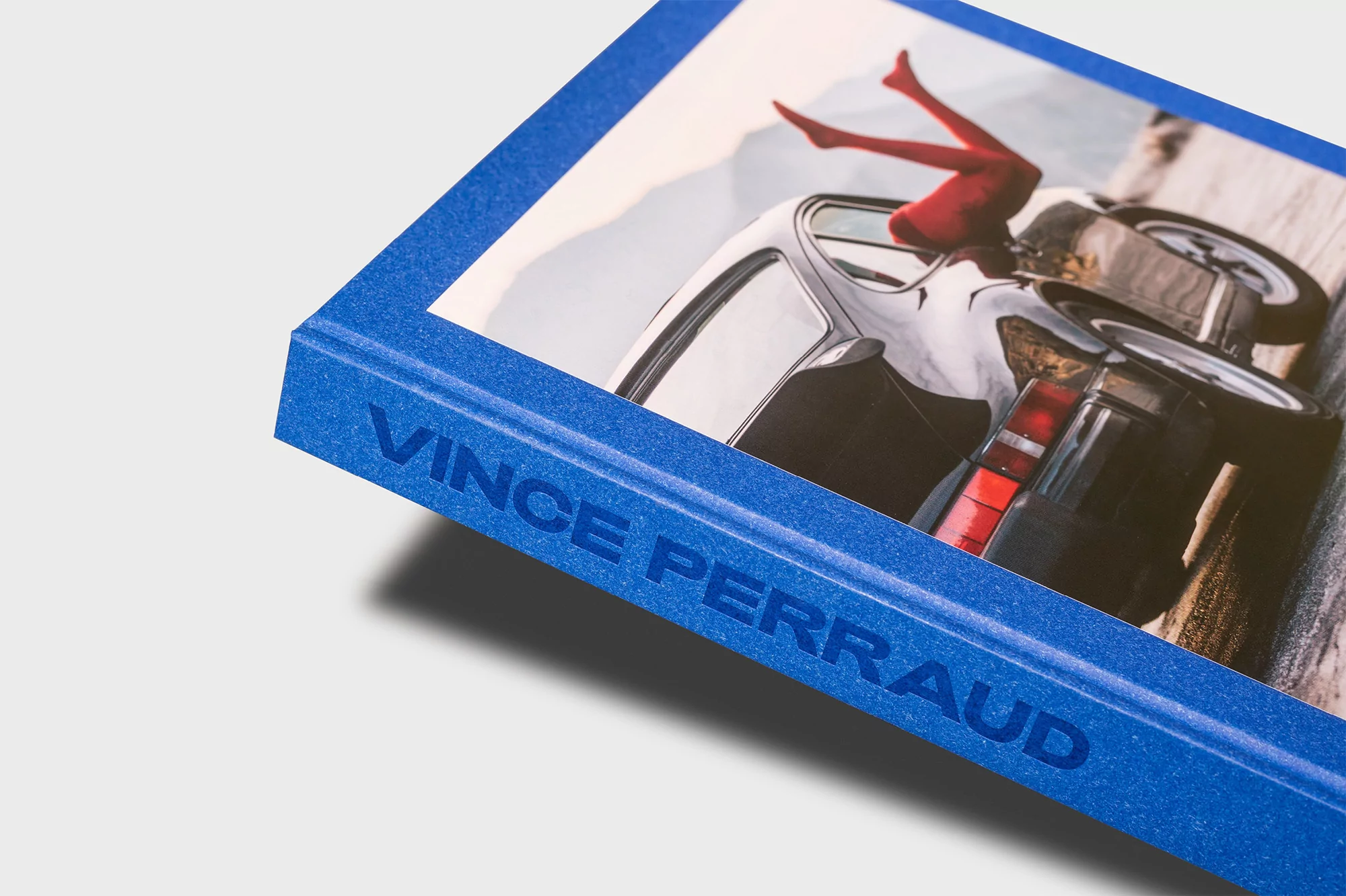 Close-up of a book cover featuring an overturned car and legs in red tights. The book is titled 'Vince Perraud'.