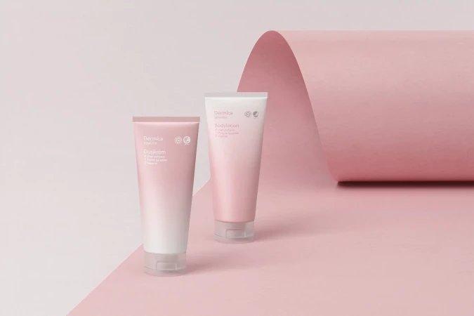 Two Dermica skincare tubes of body lotion and cream on pink backdrop. Minimalist beauty product shot for cosmetics brand promotion.