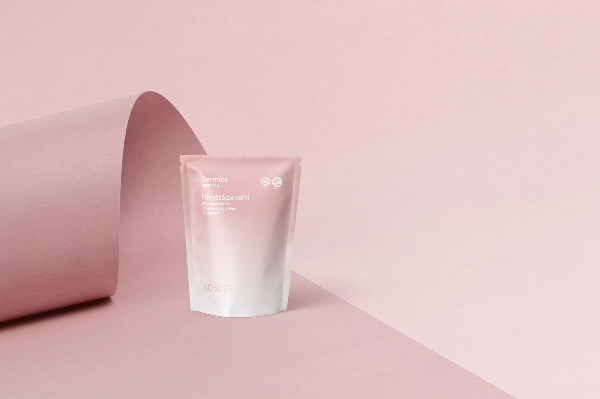 Dermica skincare refill pouch on a pink surface with a curved pink backdrop for beauty and wellness product promotion.