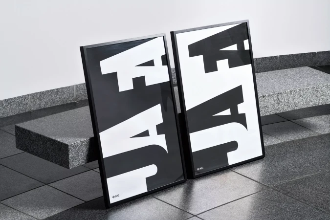 Two framed black-and-white typographic posters lean against a grey granite bench and tiled floor in an indoor environment with neutral lighting.