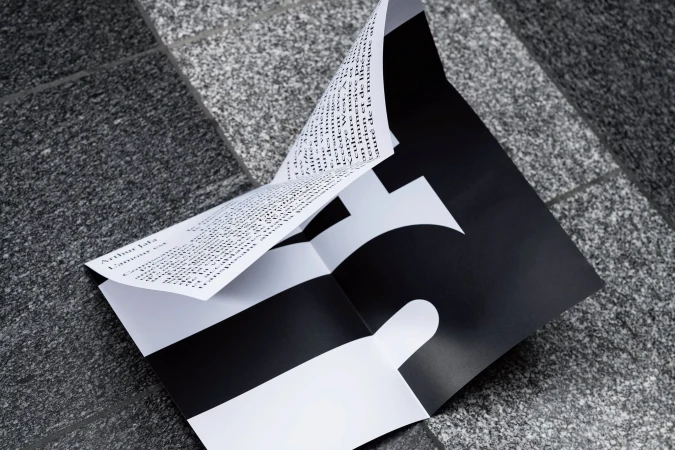 Folded black and white printed paper resting on a patterned granite surface