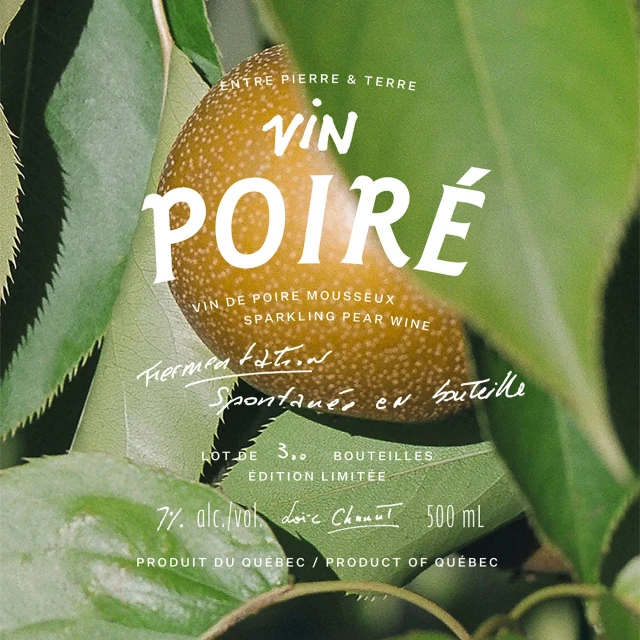 Close-up of a pear surrounded by green leaves, with text overlay for Vin Poiré, a sparkling pear wine from Quebec.