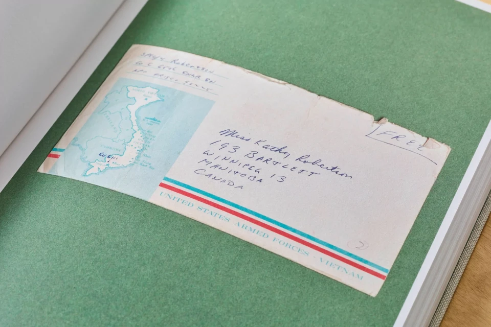 Vintage airmail envelope with a map of Vietnam, featuring handwritten addresses and postage, placed on a green page of a book.