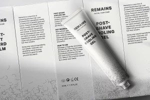 White tube of Remains post-shave cooling gel placed diagonally across branded packaging panels.