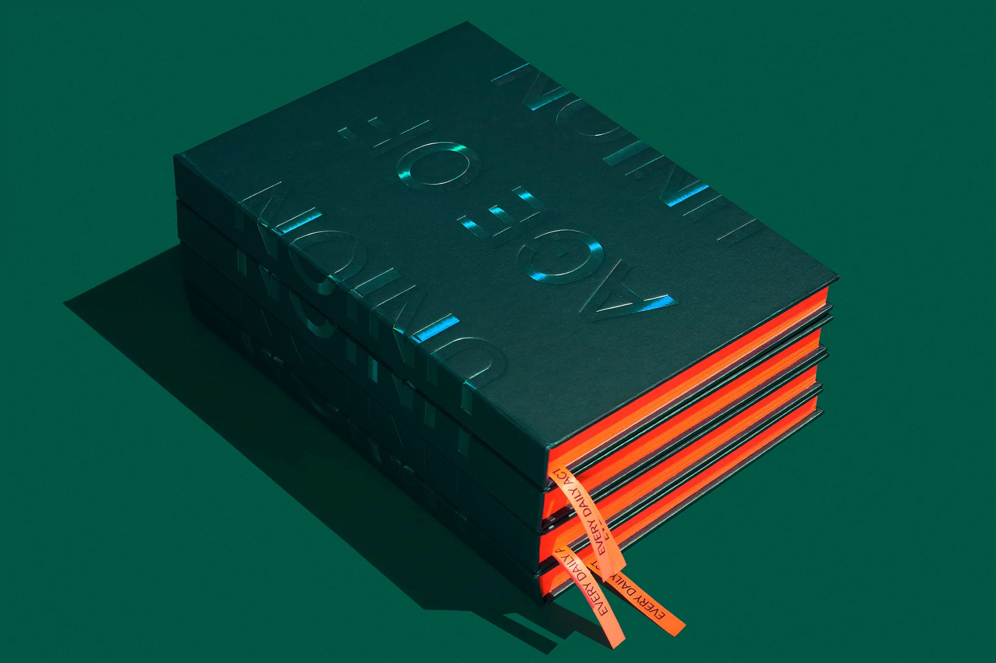 Close-up studio shot of a dark green book with neon orange edges and bookmarks on a matching green backdrop in studio lighting.