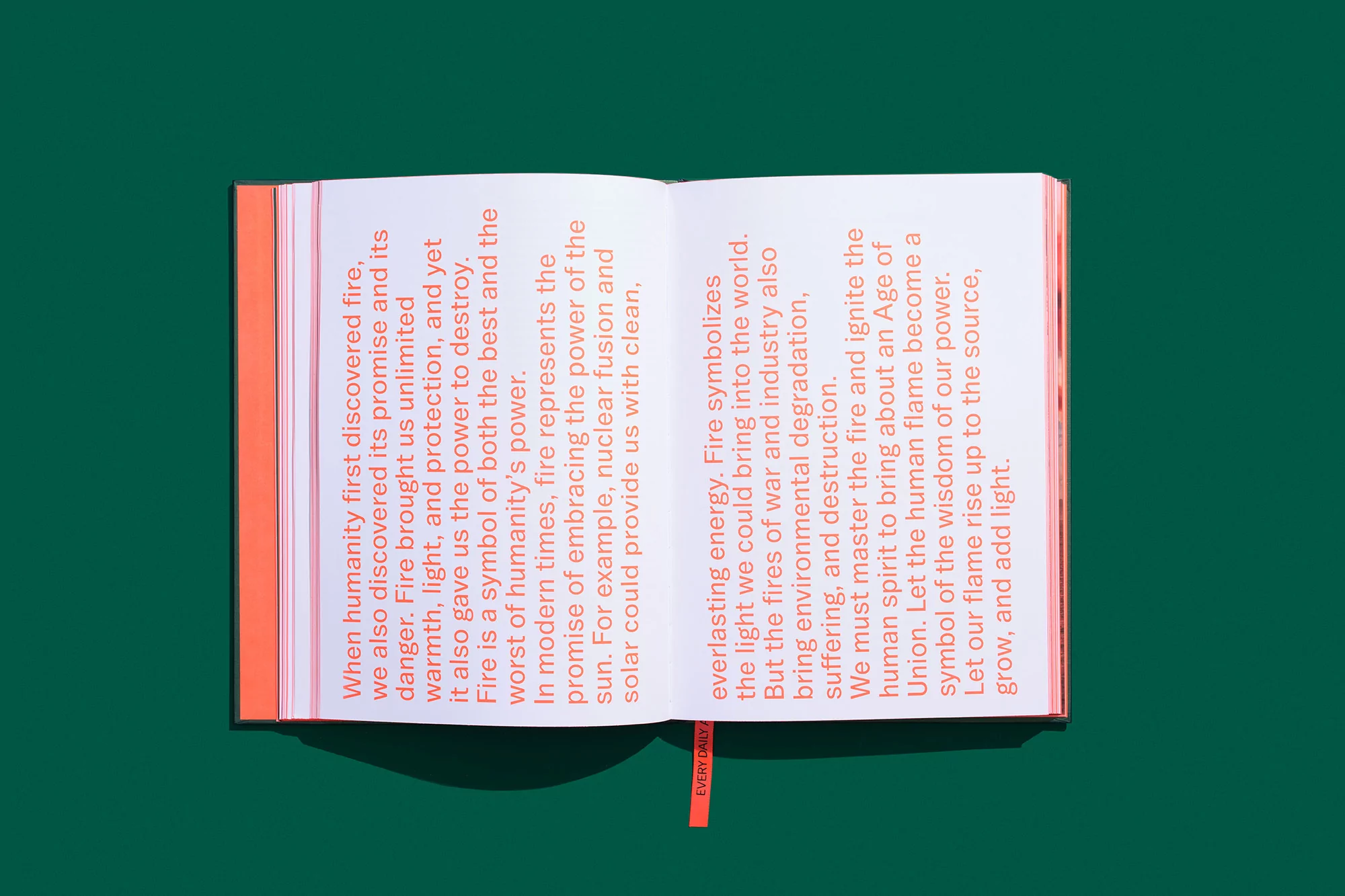 Close-up studio shot of an open book with text about fire, set against a solid green background with an attached orange bookmark.