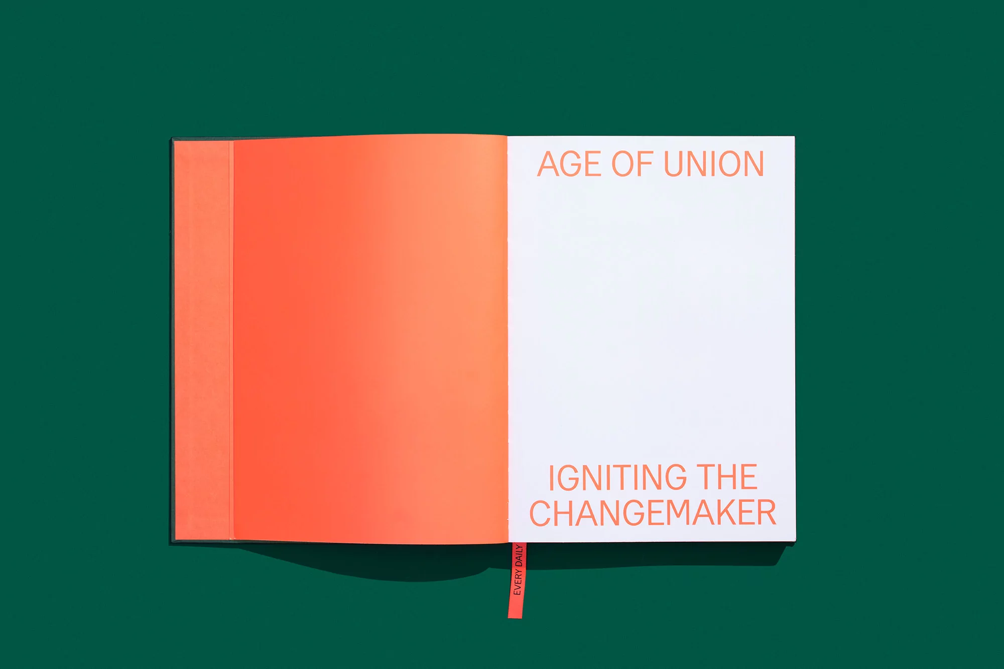 Open book with title 'Age of Union', resting on a dark green surface. Book features orange and white pages with an attached bookmark.