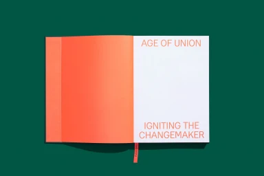 Open book with orange and white pages featuring Age of Union typography set against a dark green background
