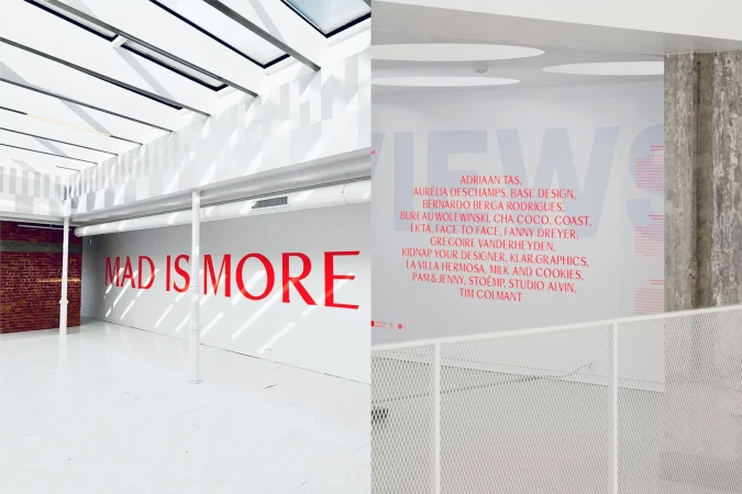 Bright open gallery space with red lettering on white walls, featuring natural skylight and minimalist architectural details.