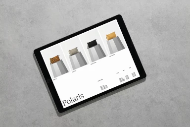 A digital tablet displaying an e-commerce website product page for leather handbags resting on a grey concrete surface